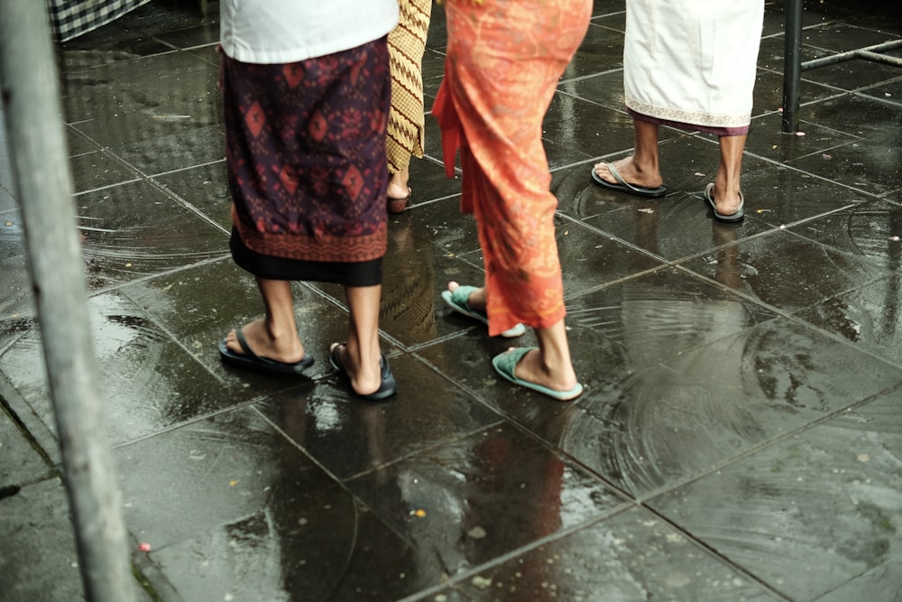 a group of people standing on a wet sidewalk