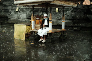 a man sitting on a bench in the rain