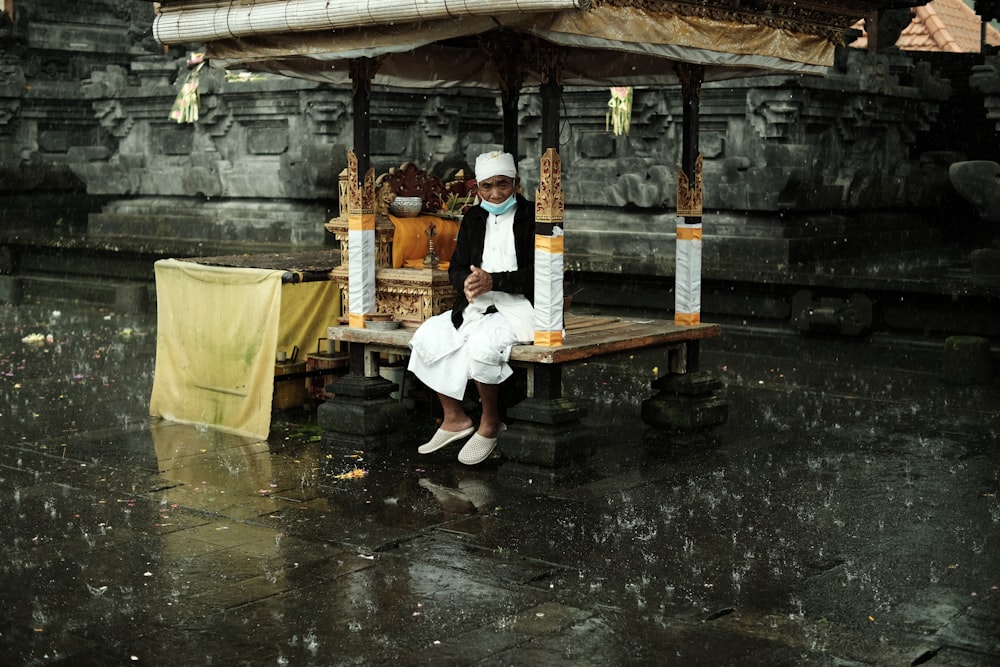 a man sitting on a bench in the rain