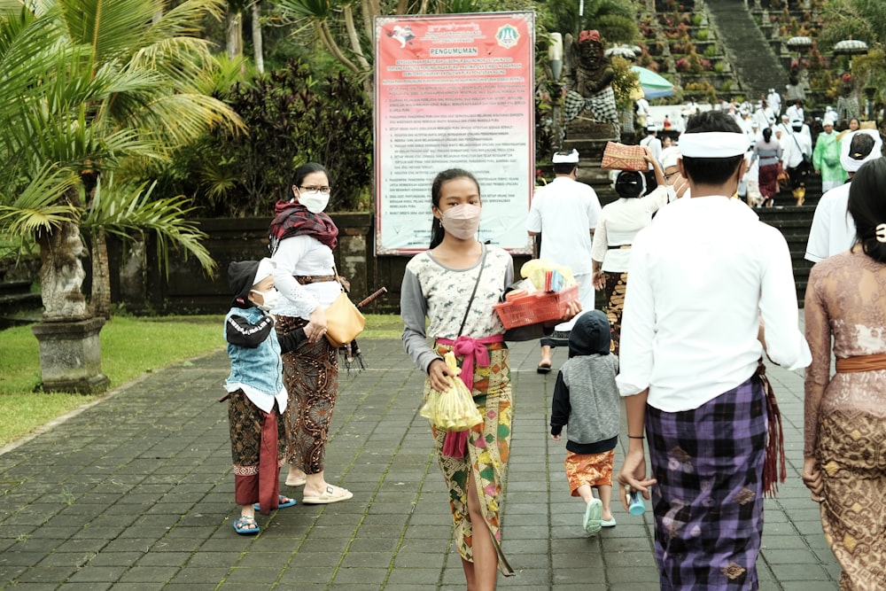 a group of people walking down a sidewalk wearing face masks