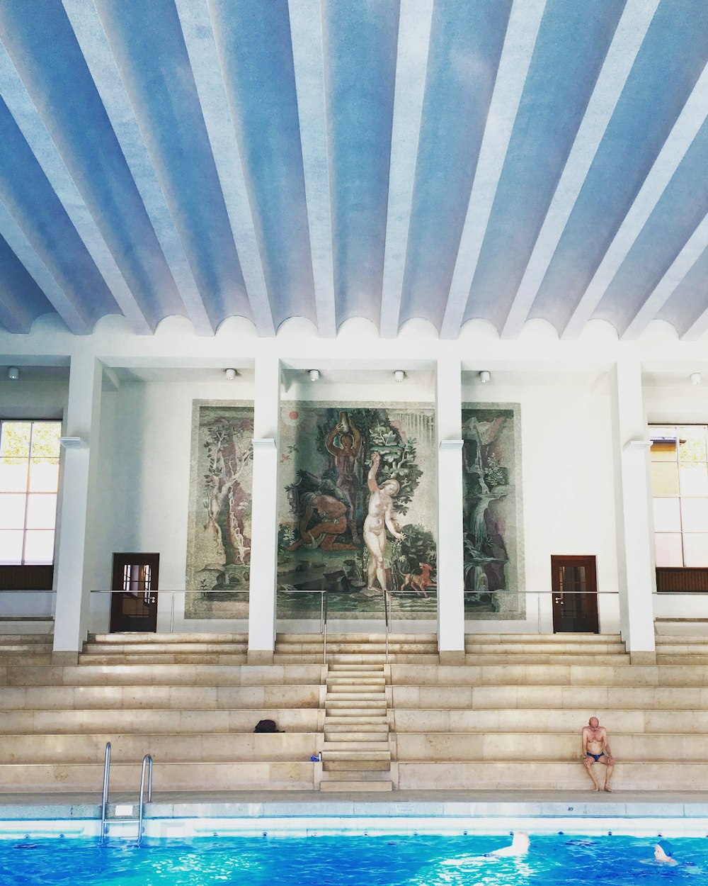 a woman sitting on the steps of a swimming pool