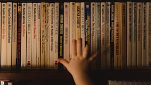 a hand reaching for a book on a shelf