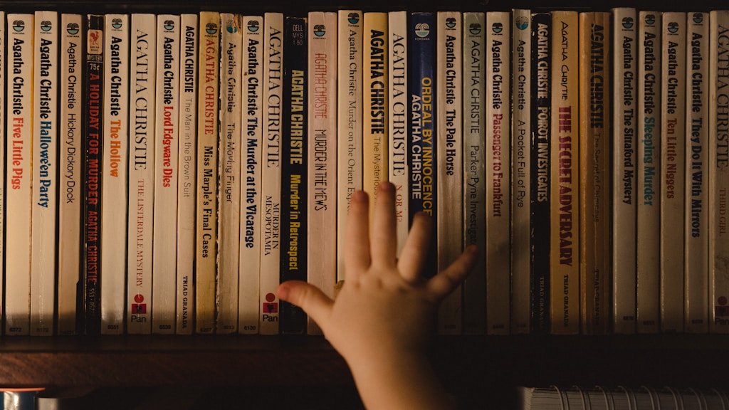 a hand reaching for a book on a shelf