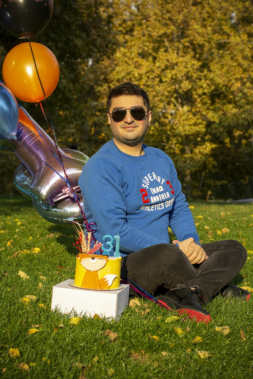 a man sitting in the grass with a birthday cake