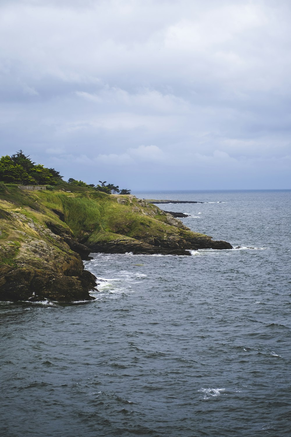 a large body of water sitting next to a lush green hillside