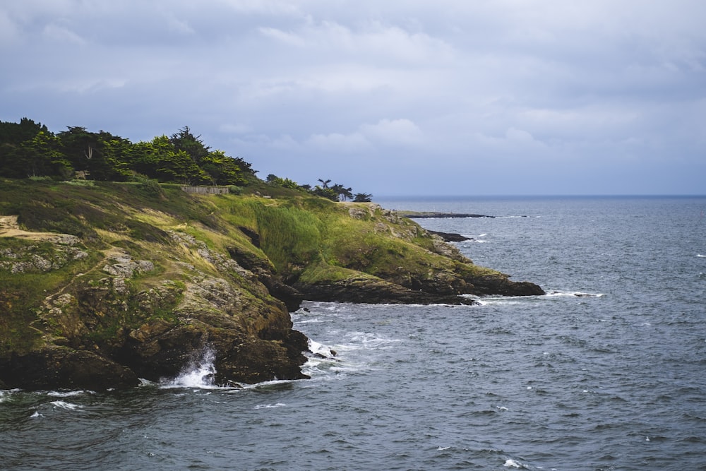 a large body of water next to a lush green hillside