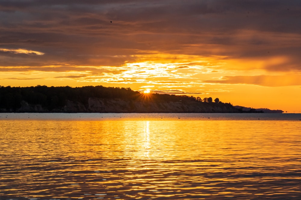 Die Sonne geht über einem See mit einer kleinen Insel in der Ferne unter