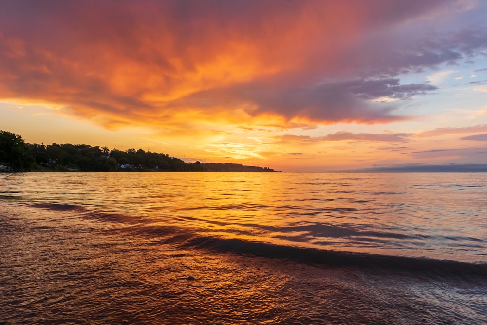 a sunset view of a beach with waves coming in