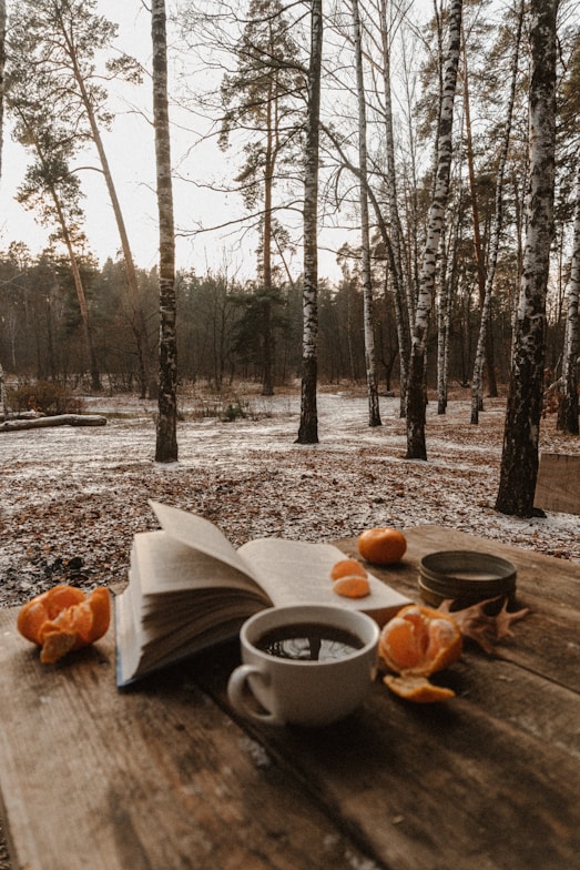 an open book and a cup of coffee on a wooden table