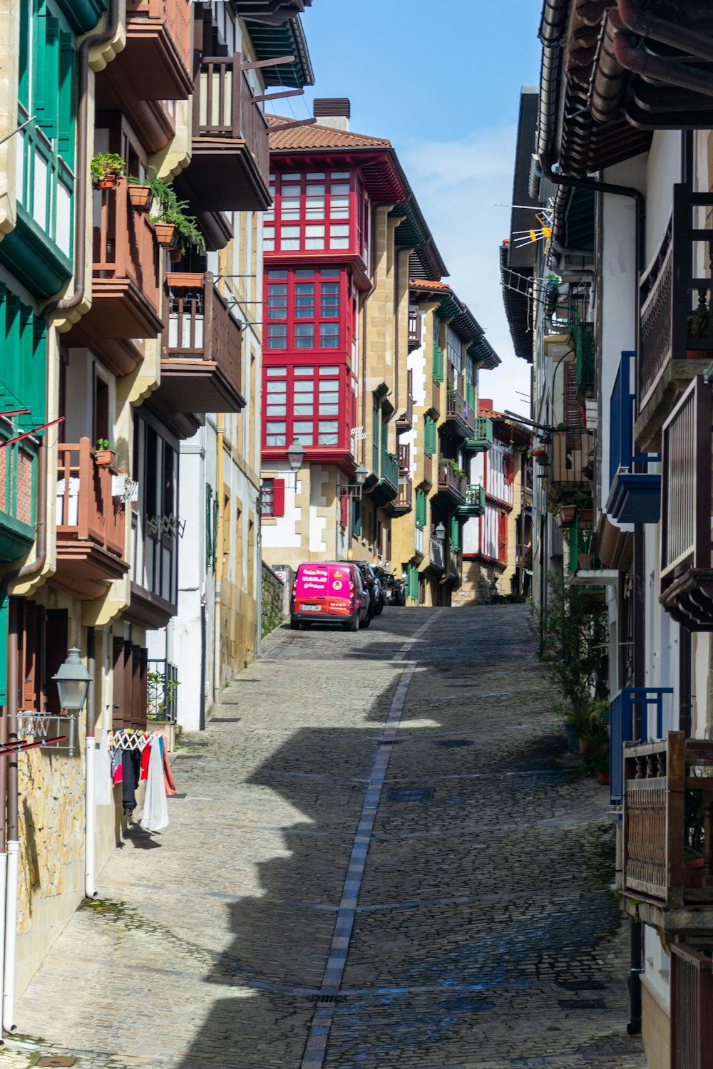 a pink car is parked on a cobblestone street