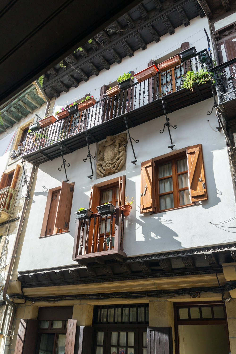 a white building with brown shutters and wooden balconies