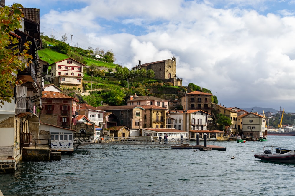 a body of water with houses on a hill in the background