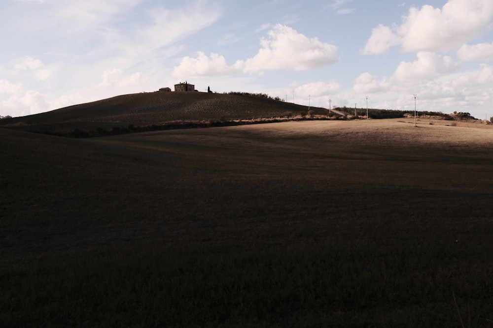 une colline herbeuse avec un bâtiment au sommet