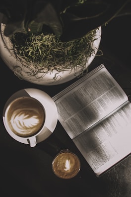 A cozy coffee setup with a book and a plant.