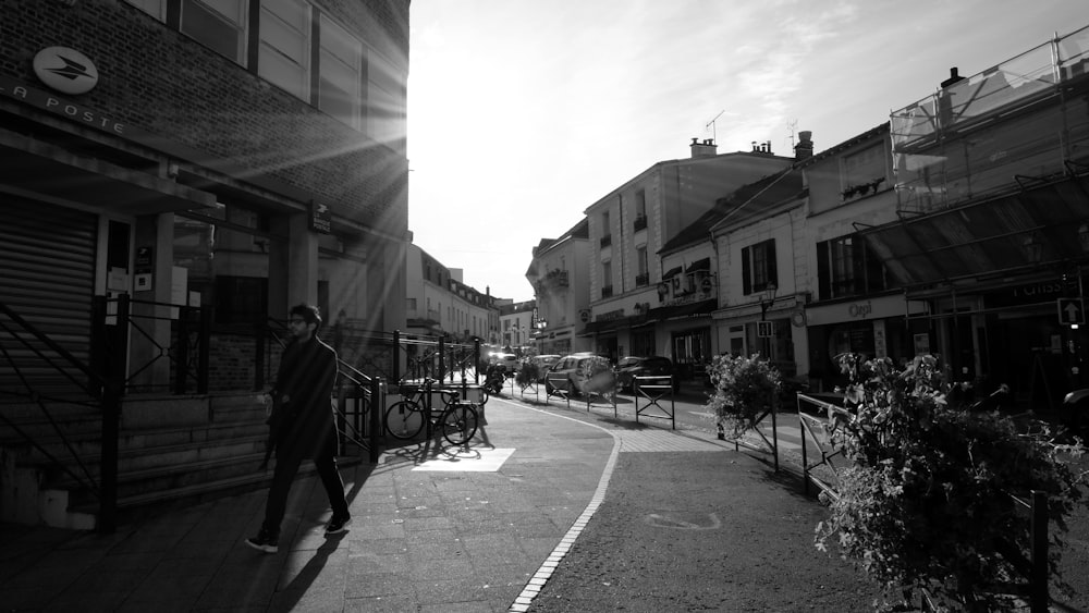 a man walking down a street next to tall buildings