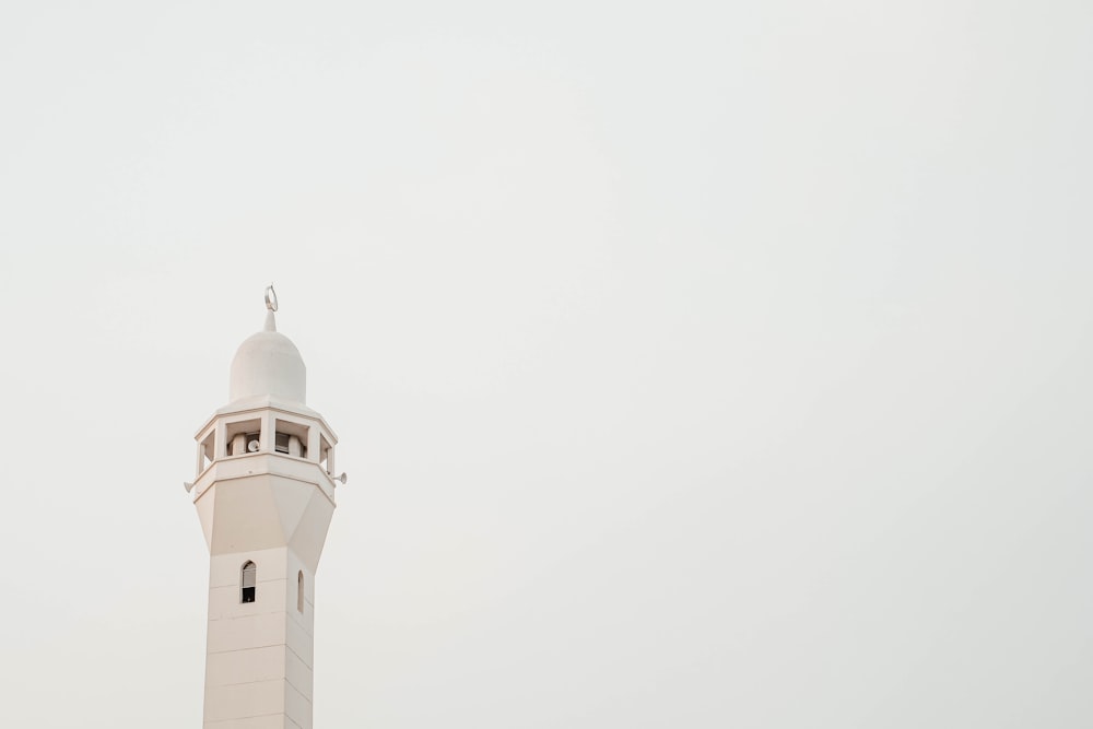 a tall white tower with a clock on it's side