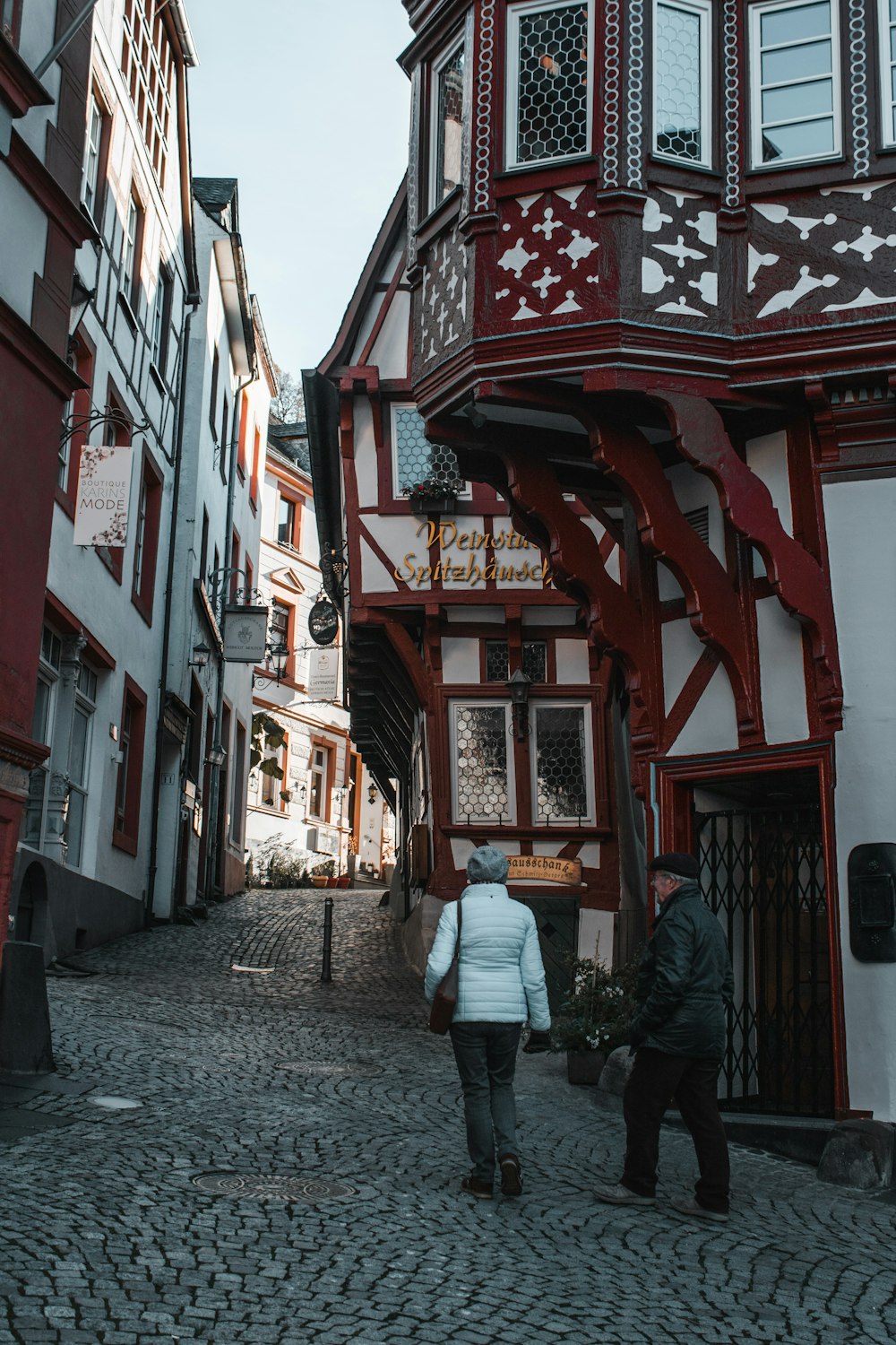 a couple of people walking down a cobblestone street