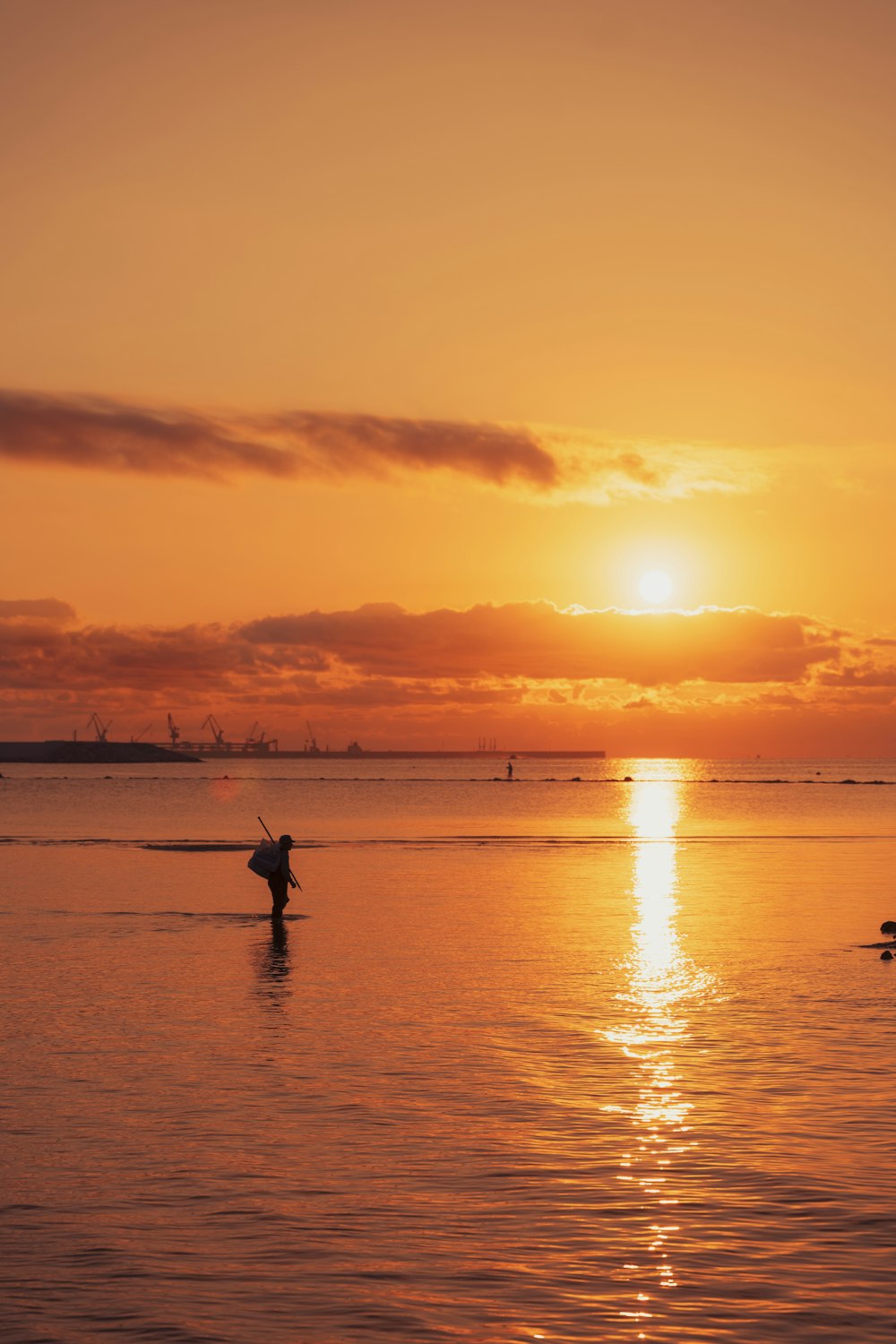 uma pessoa em uma prancha de surf na água ao pôr do sol