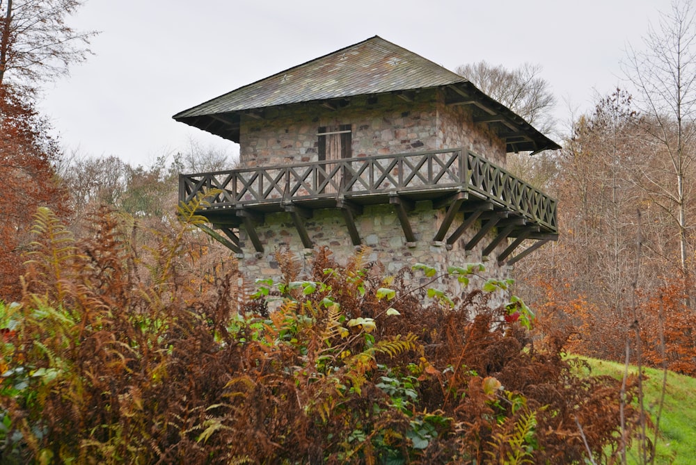 a stone building with a balcony in the middle of a forest