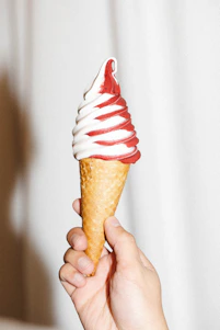 Close-up of creamy soft serve ice cream in a vintage red and white cone holder.