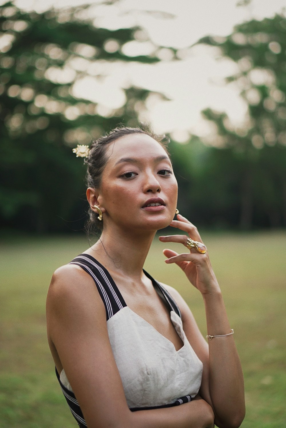 a woman standing in a field with a flower in her hair