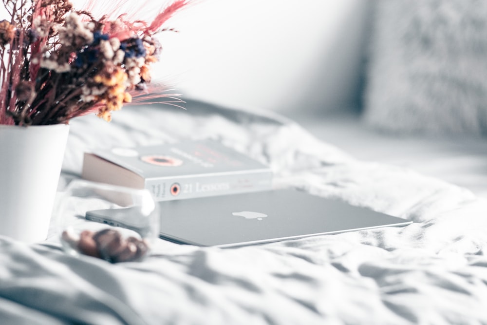 a white vase filled with flowers next to a laptop