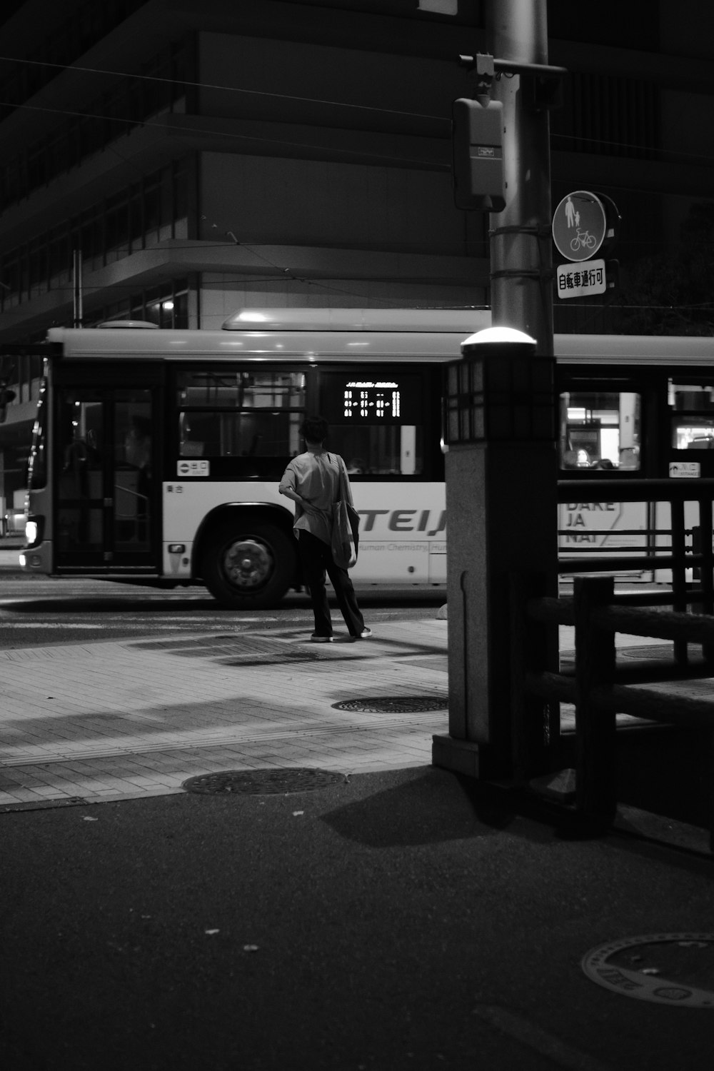 a black and white photo of a man crossing the street