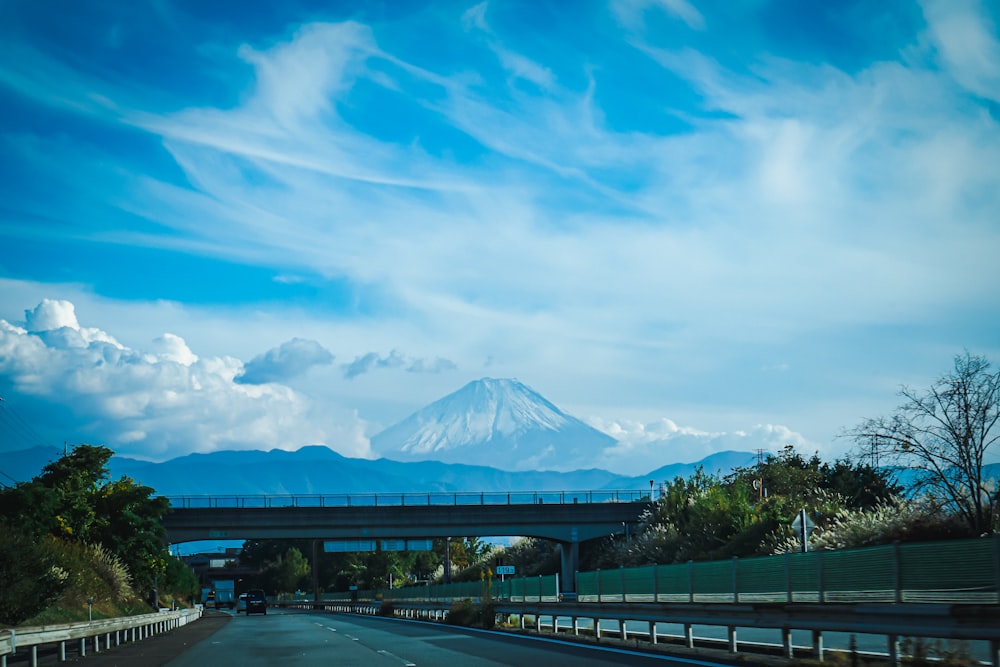 a highway with a bridge and a mountain in the background