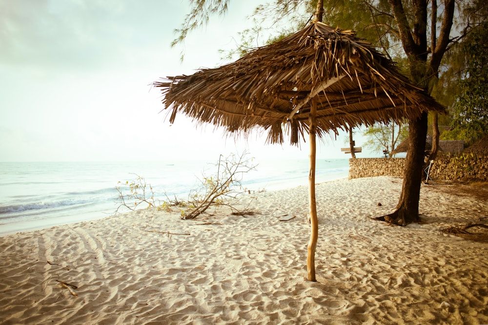 a straw umbrella sitting on top of a sandy beach