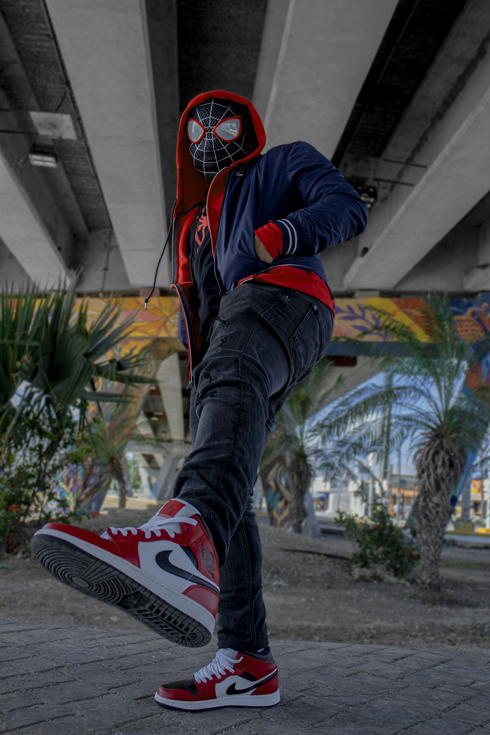 a man in a spider man mask is doing a trick on a skateboard