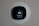 A smart thermostat is mounted on a wall, displaying the temperature set to 69 degrees. The device has a modern, sleek design with a black faceplate surrounded by a white circular backplate. Various sensor icons and settings are visible on its digital display.