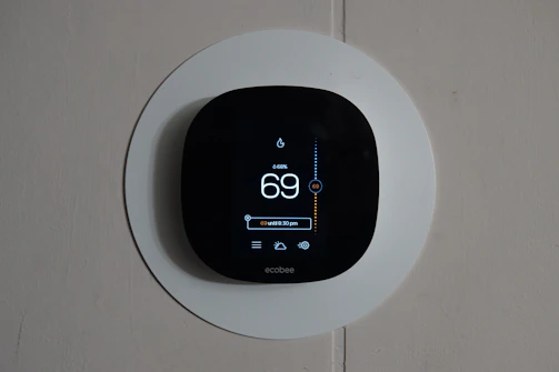A friendly technician setting up a smart thermostat in a cozy living room.