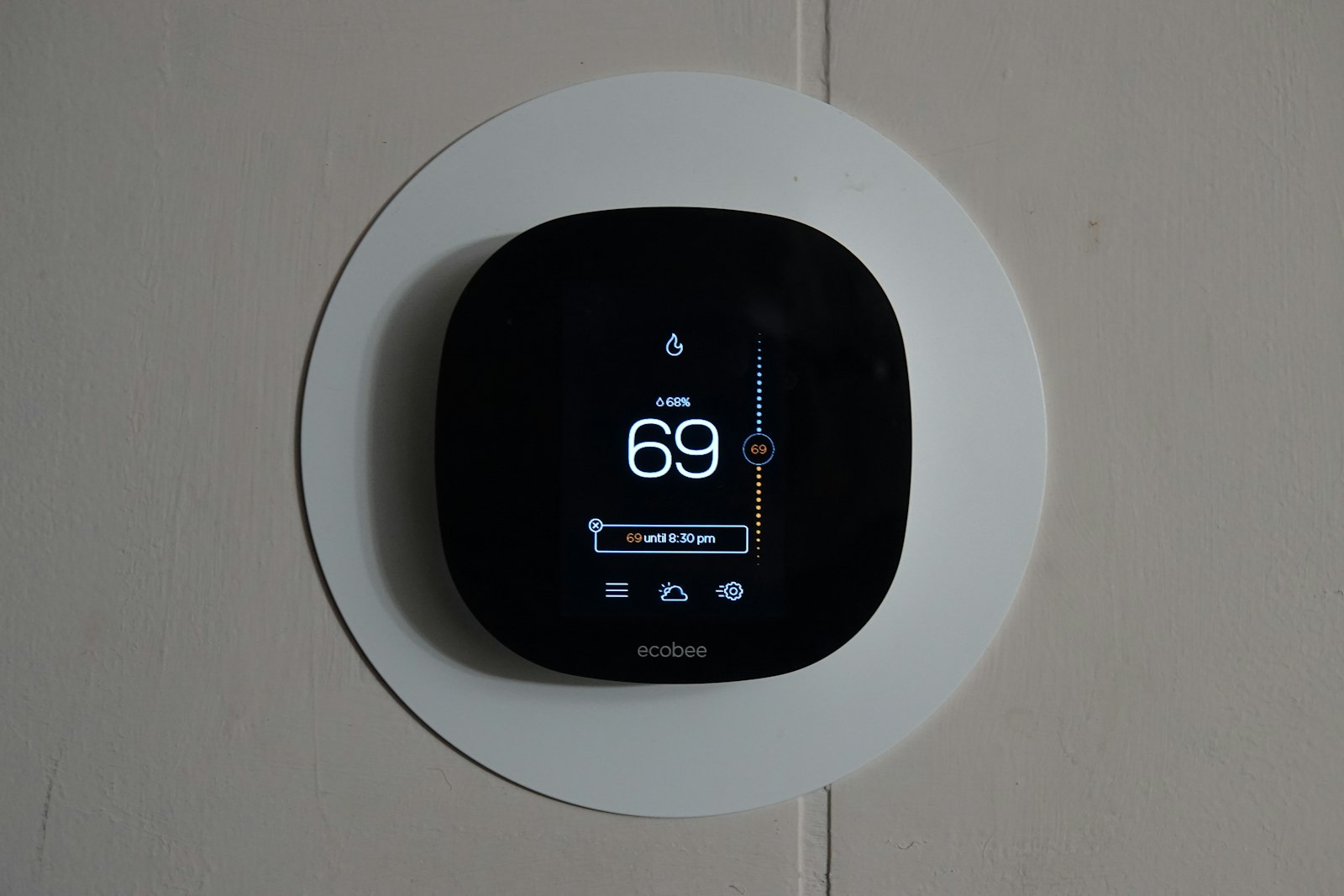 A smart thermostat mounted on a white wall