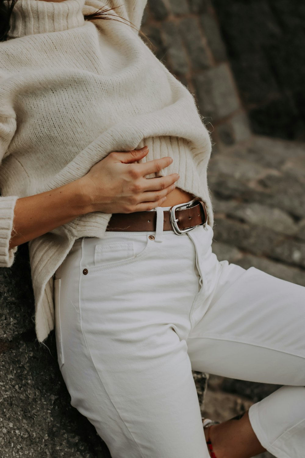 a woman wearing white jeans and a sweater