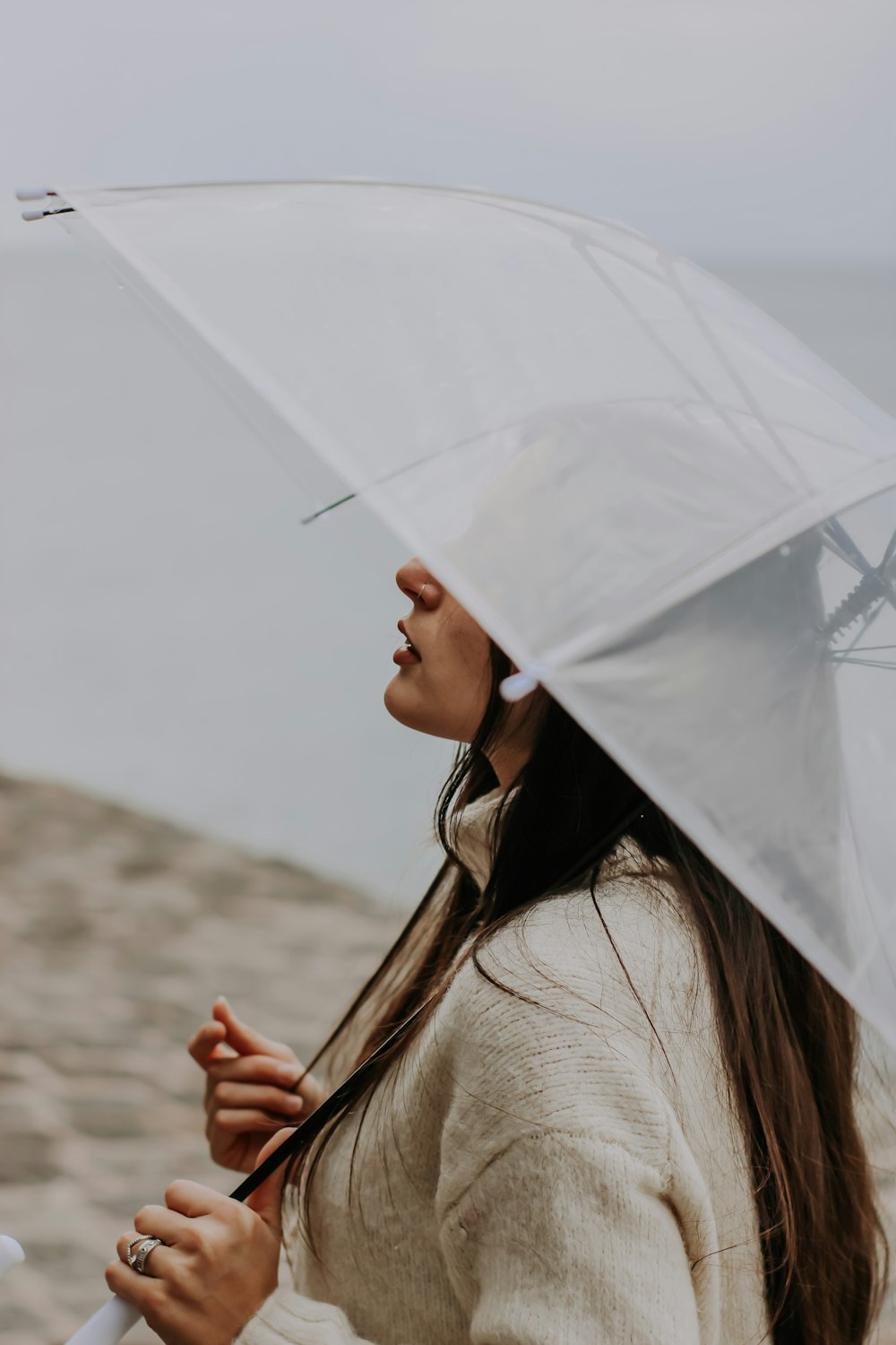 a woman standing on a beach holding an umbrella