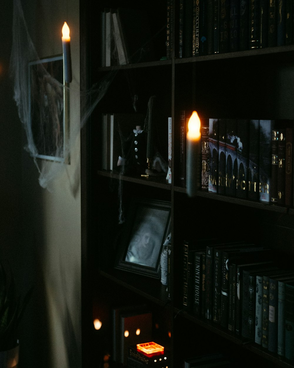 a dark room with bookshelves and a lit candle