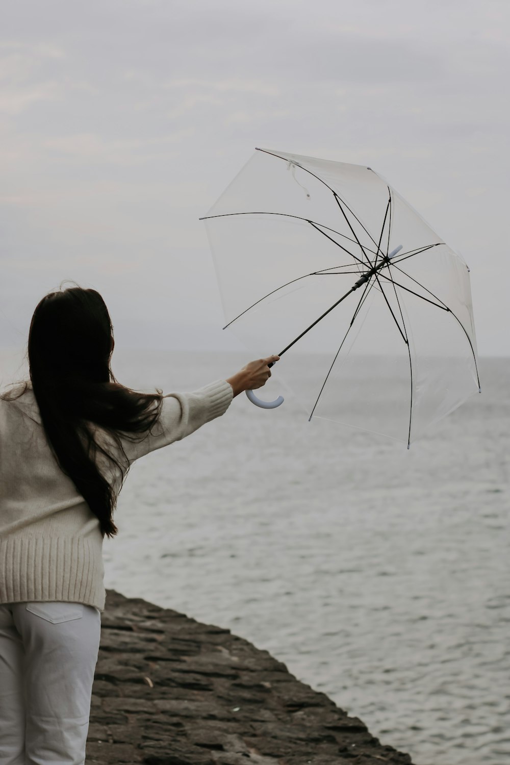 a woman holding an umbrella near the ocean