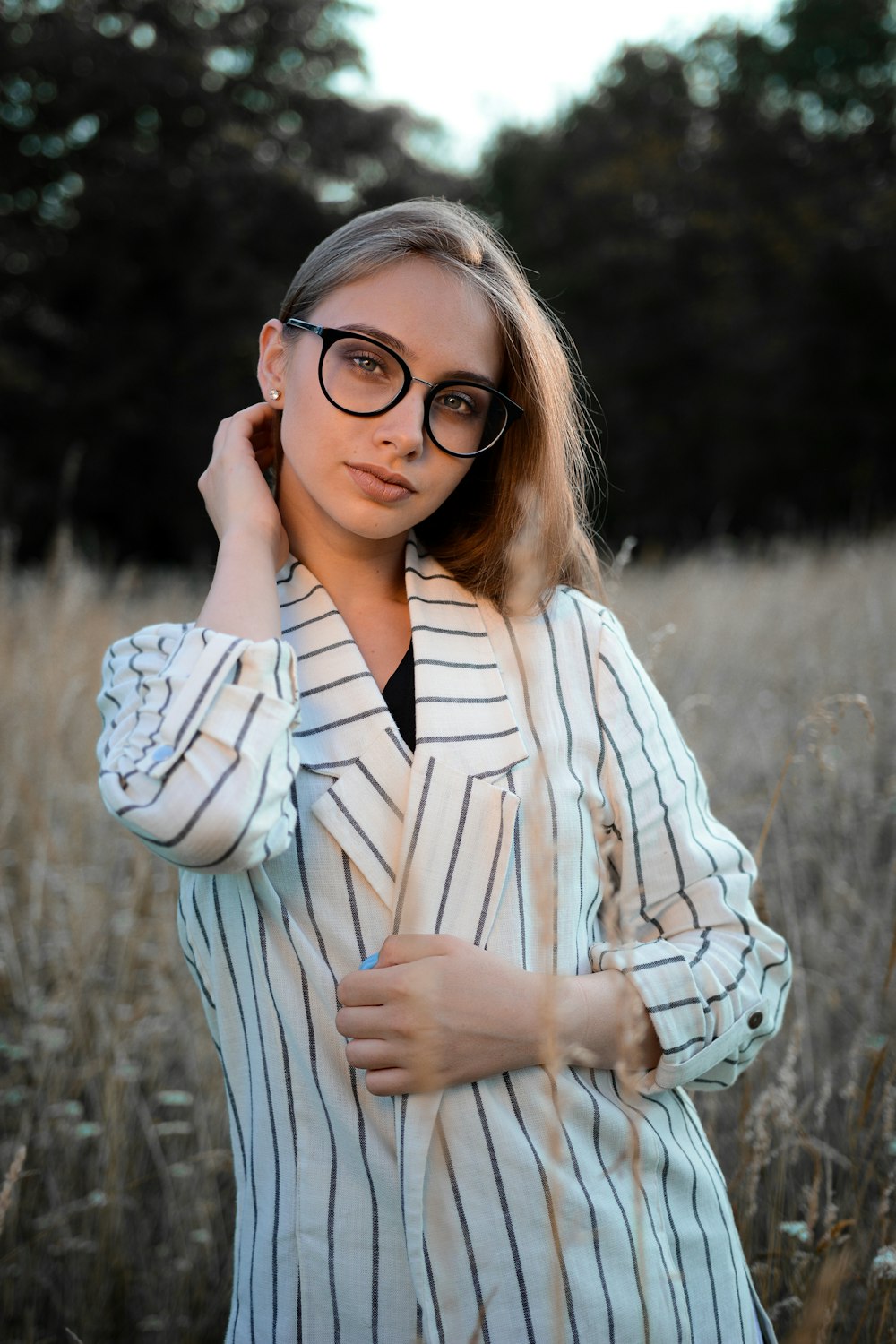 a woman wearing glasses standing in a field