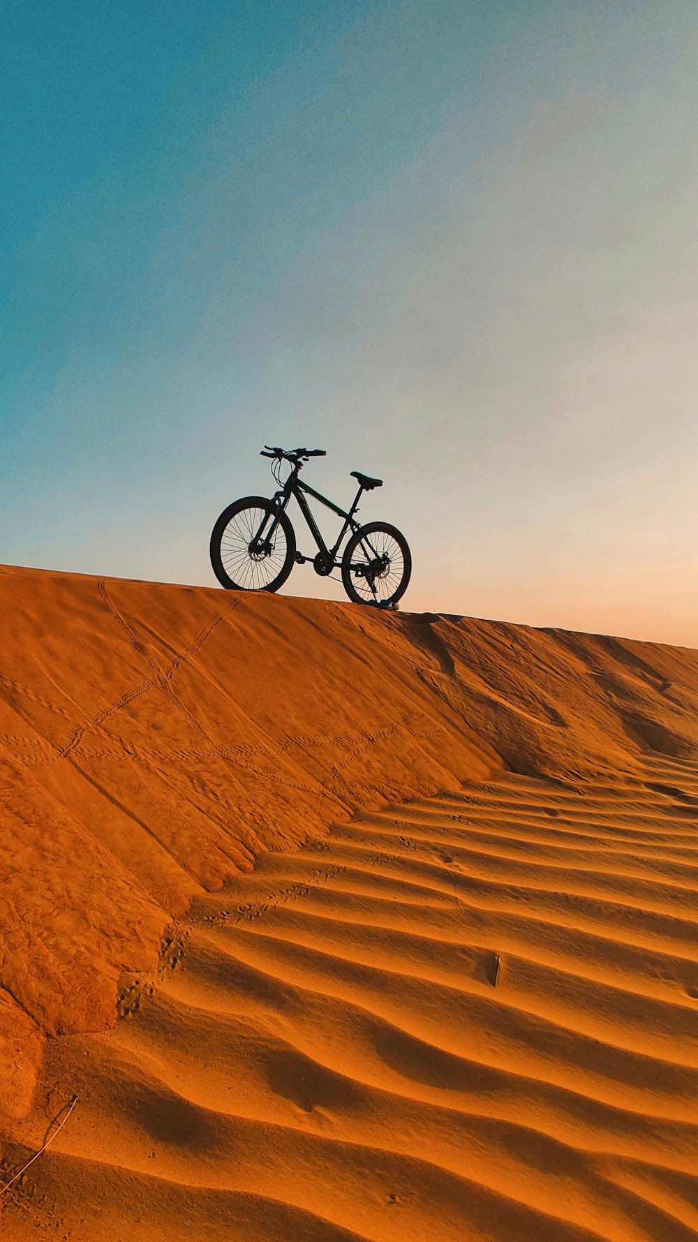 a bike is sitting on top of a sand dune