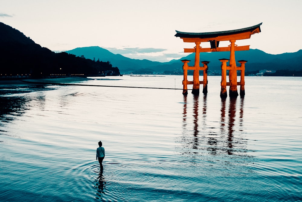 a person standing in the water in front of a floating tori tori