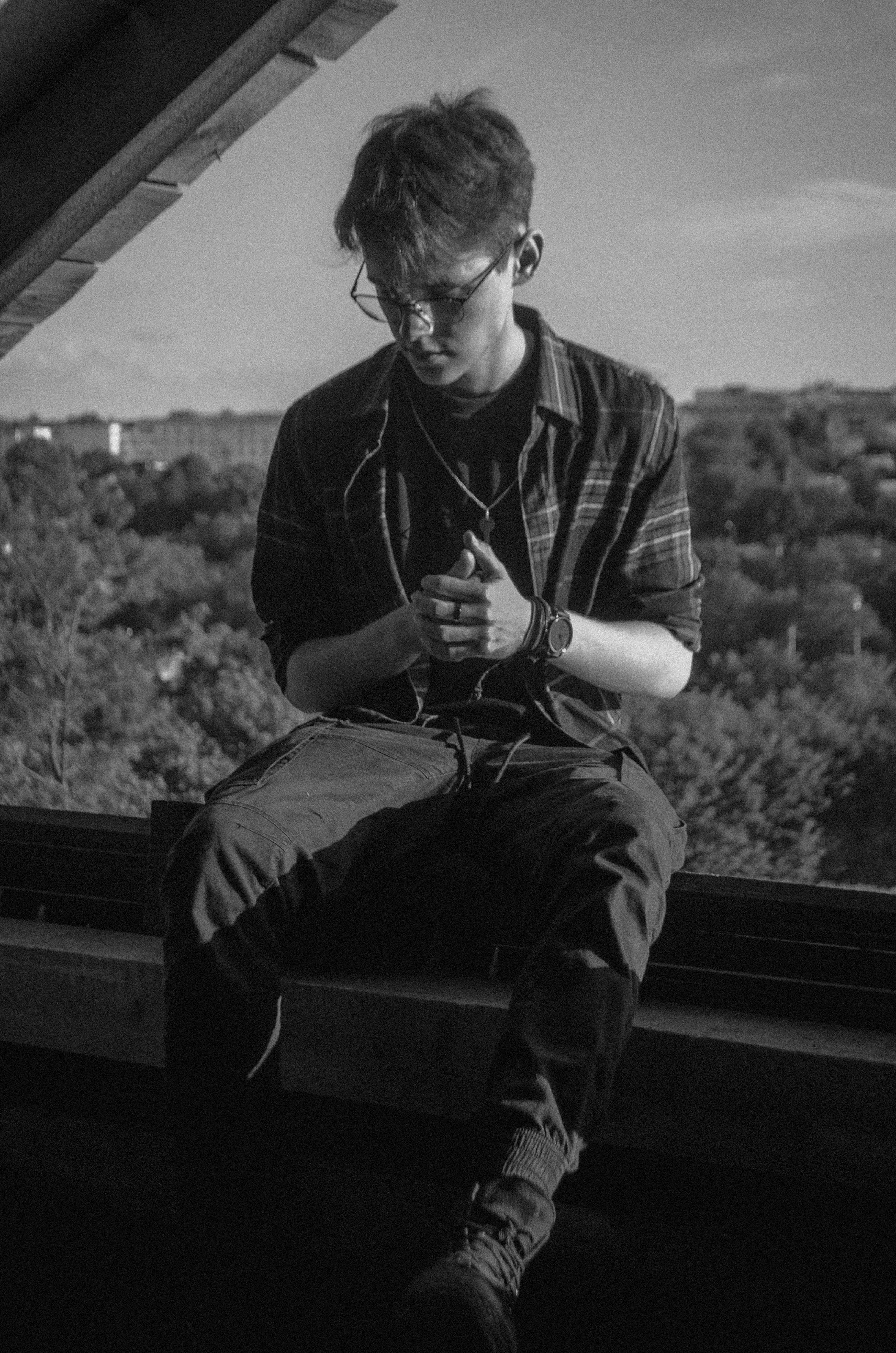 A man sitting on a ledge looking at his cell phone photo – Free Grey ...