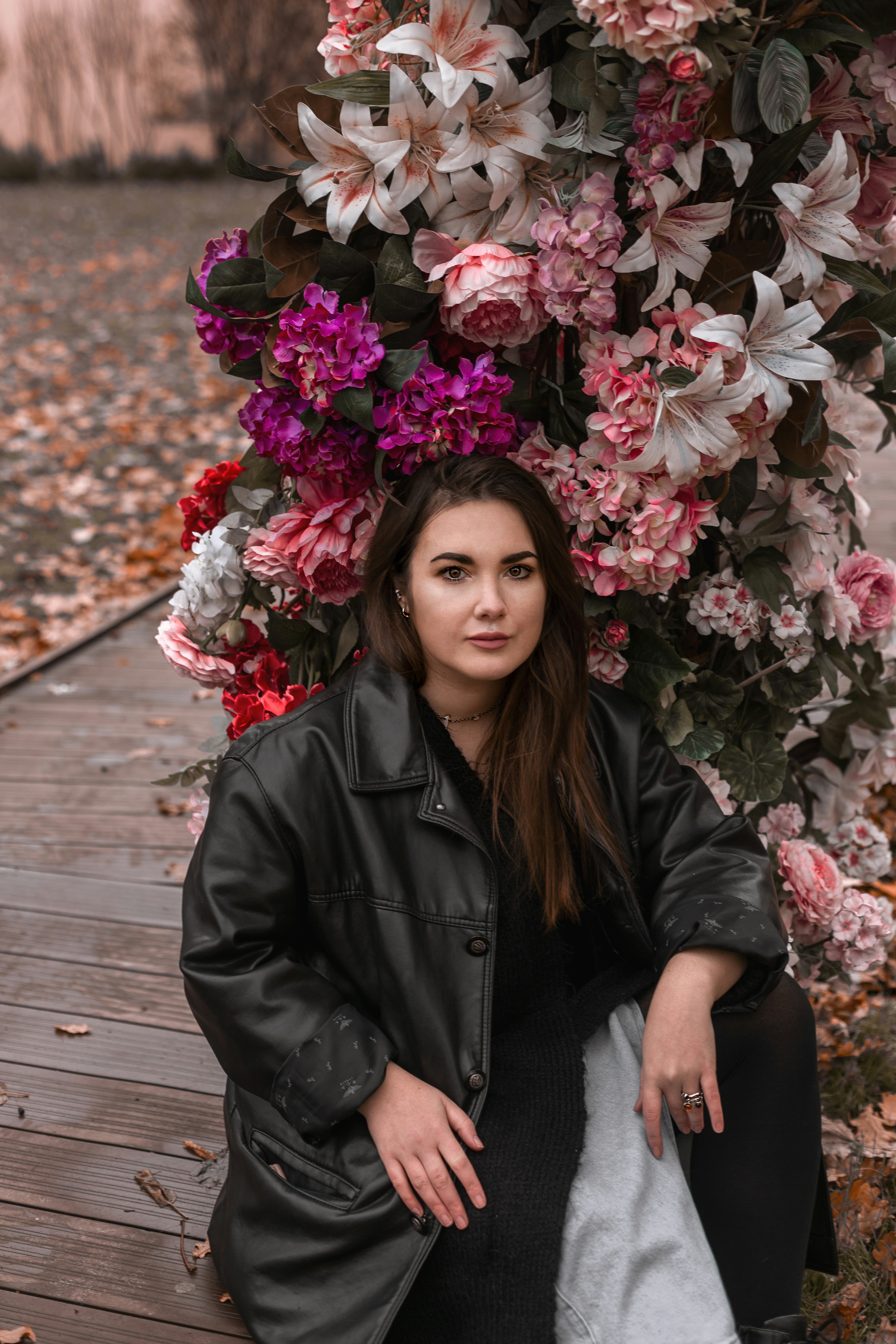 a woman sitting on a wooden floor next to a bunch of flowers