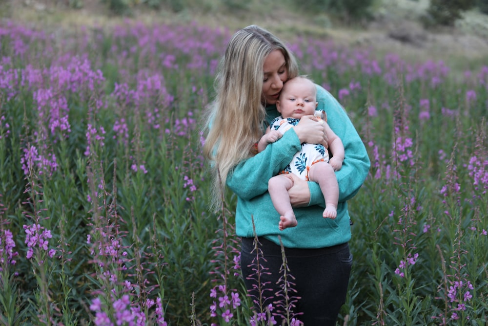 a woman holding a baby in a field of purple flowers