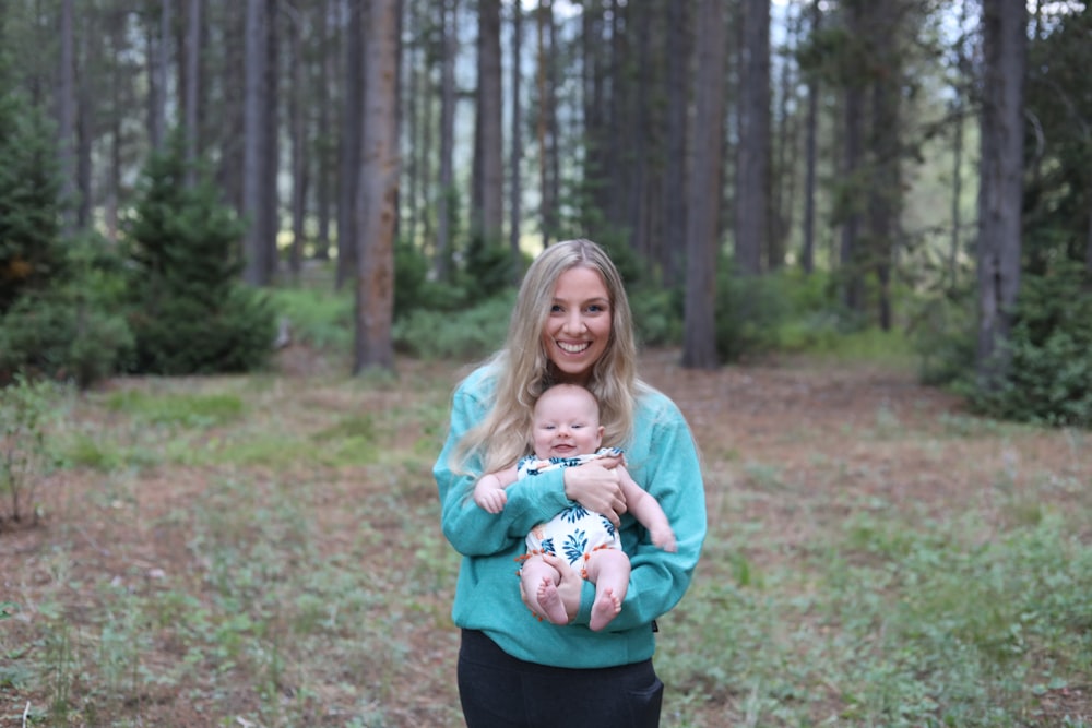 a woman holding a baby in a forest