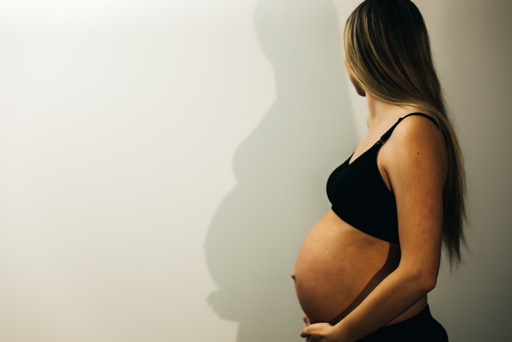 a pregnant woman standing in front of a white wall