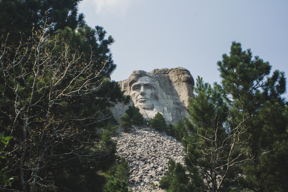 a statue of abraham on top of a mountain surrounded by trees
