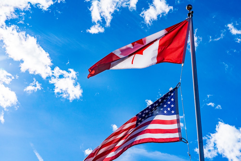 two american and canadian flags flying in the wind