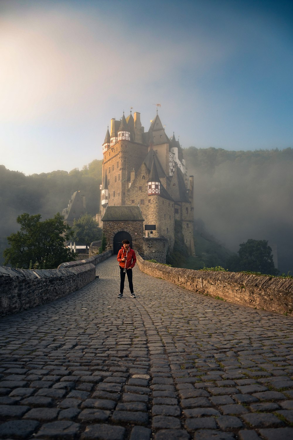 Una persona parada en un camino empedrado frente a un castillo