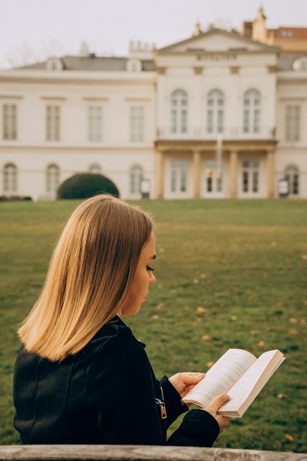 a woman sitting on a bench reading a book