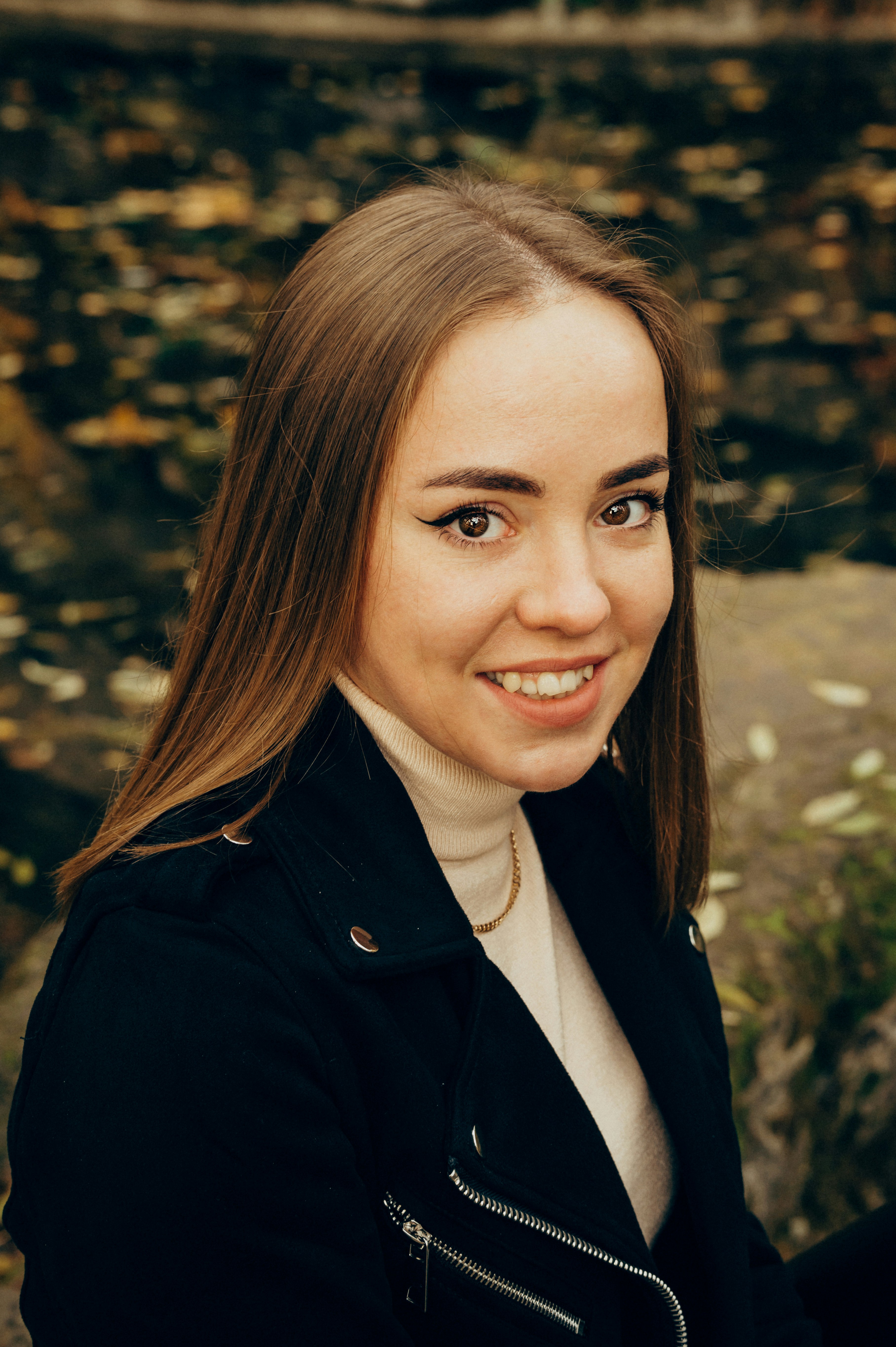 Eine Frau in schwarzer Jacke, die in die Kamera lächelt